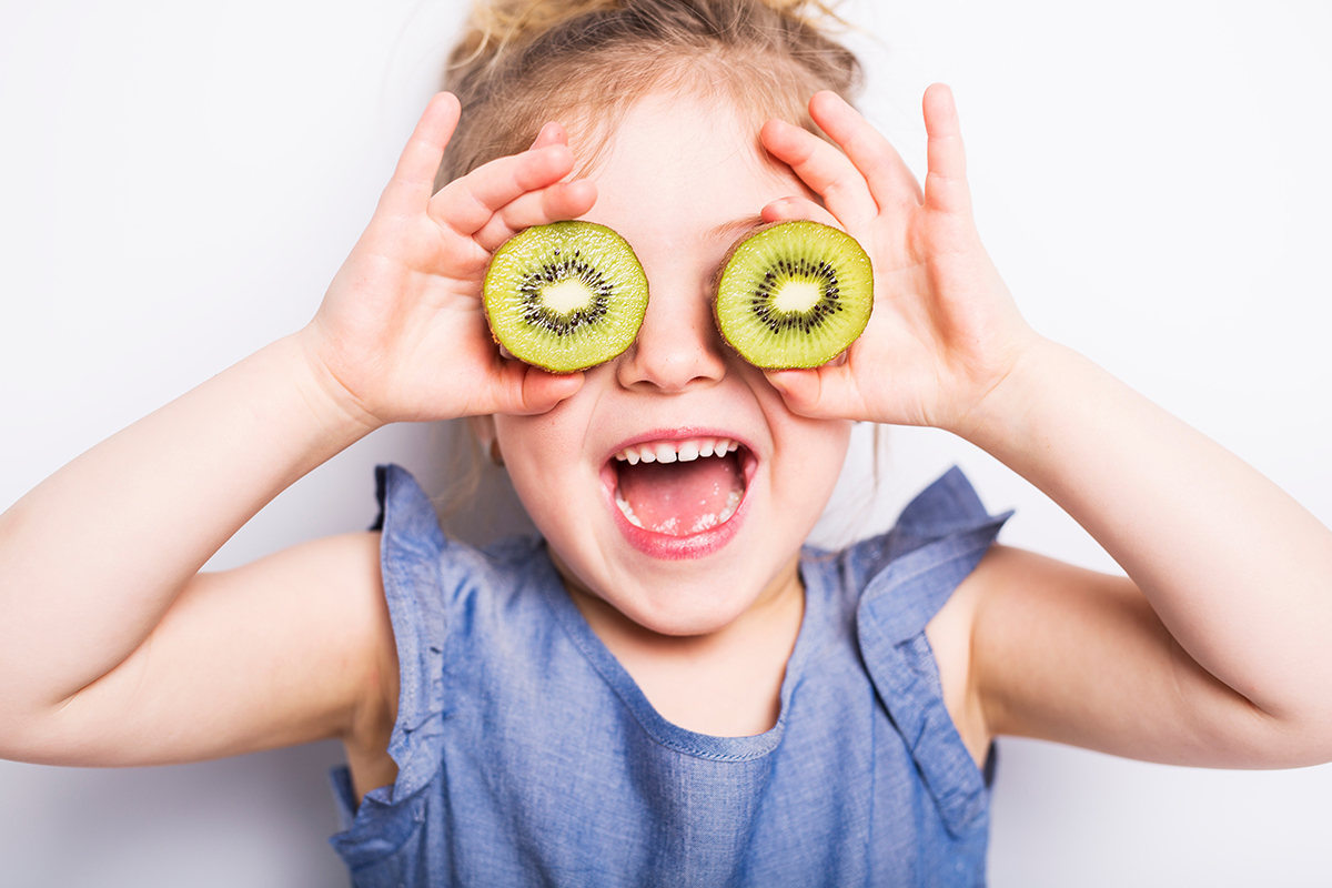 Beautiful girl child holding kiwi